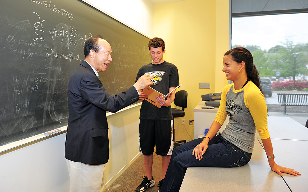 two students with faculty in classroom