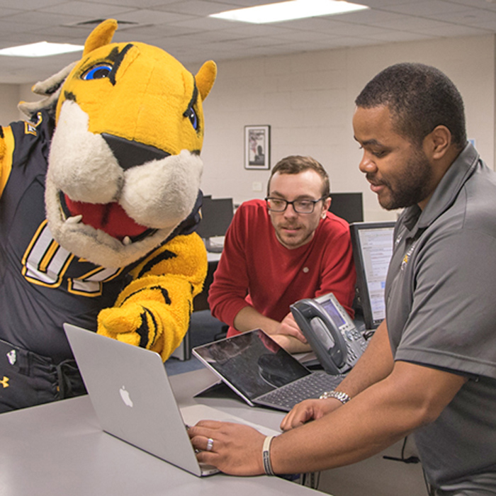 mascot and student assisted at the Technology Support Desk service desk