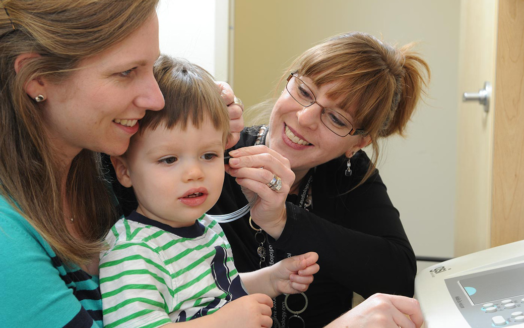 Professor and student helping child with audio test