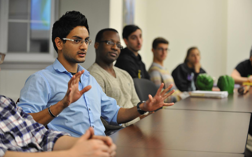 Student talking in classroom setting with other students in background