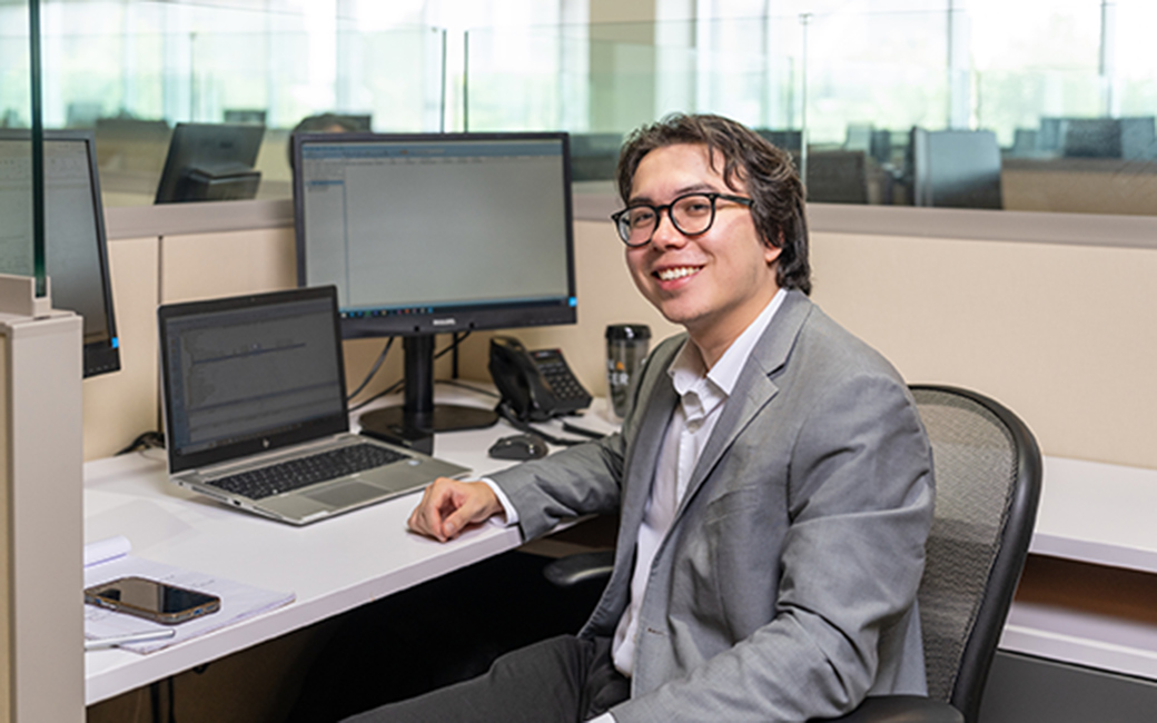 student poses at computer at internship