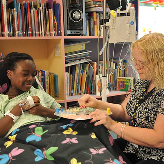 Child life intern playing a board game with a sick child