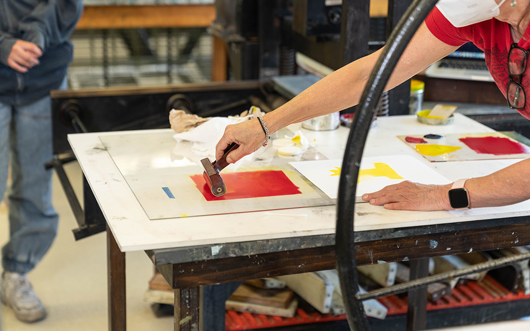 up close image of ink being rolled for printmaking, press wheel in foreground