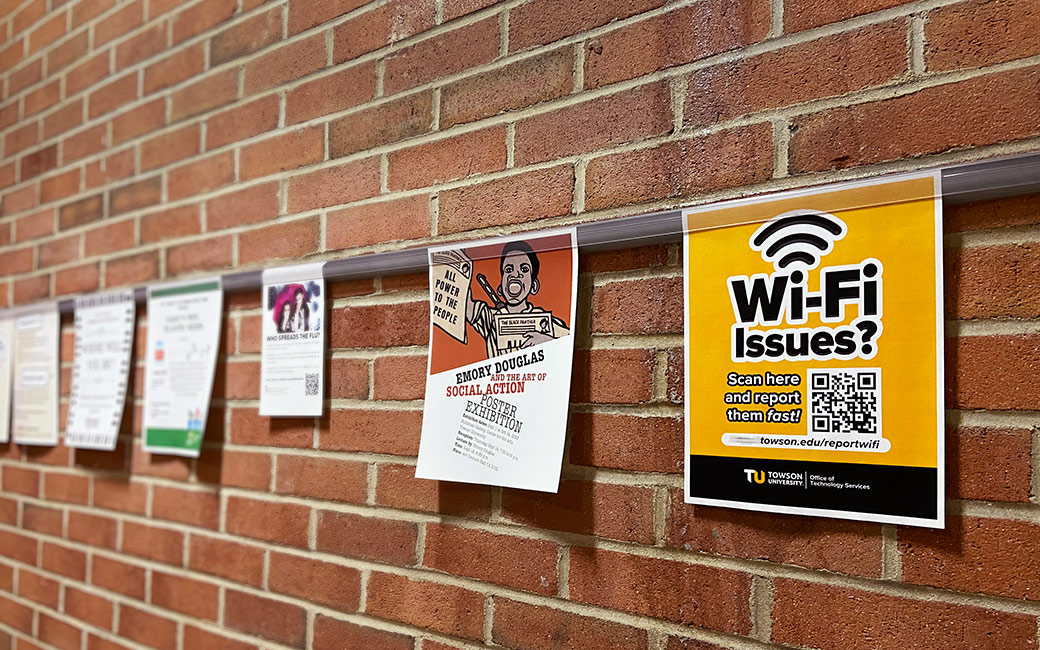 A row of hung up flyers line a brick wall