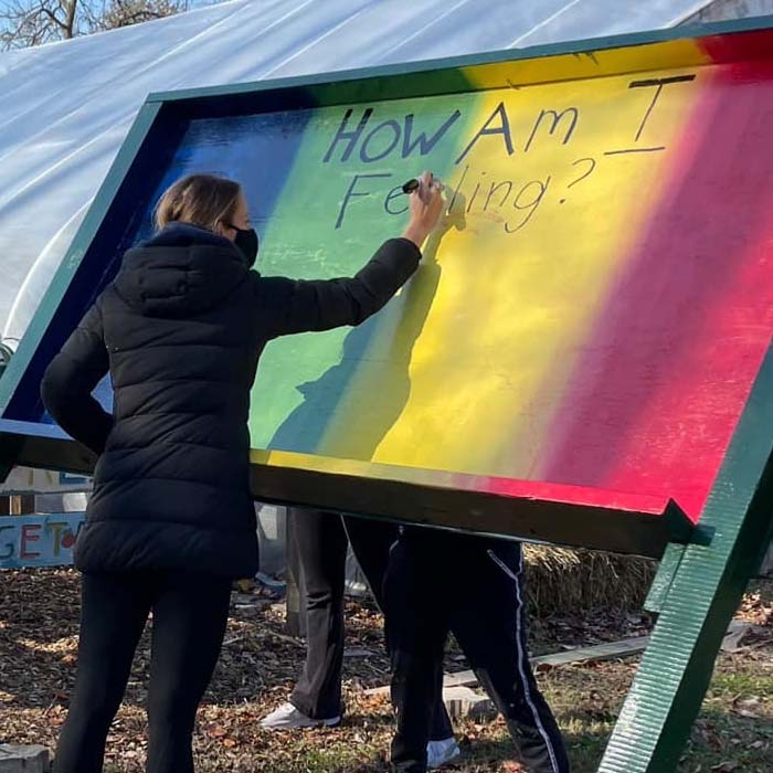 Student writing on a community sign