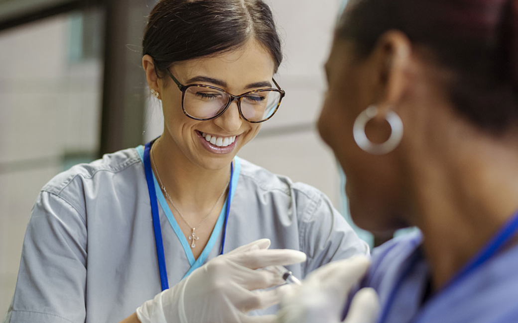 certified clinical medical assistant administering injection in arm of young woman