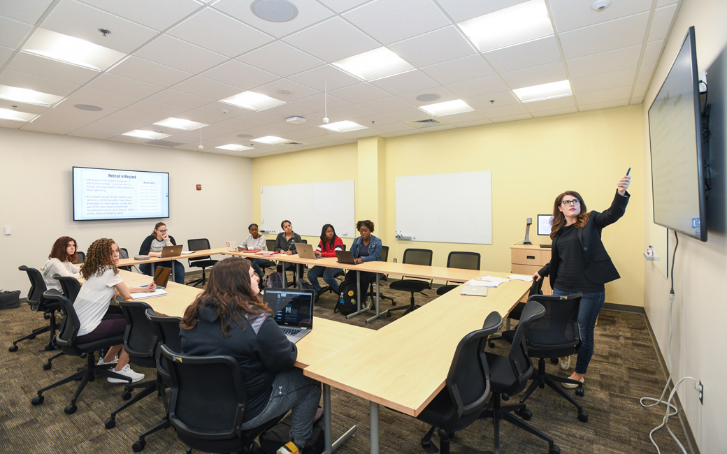 Professor standing at screen showing students information