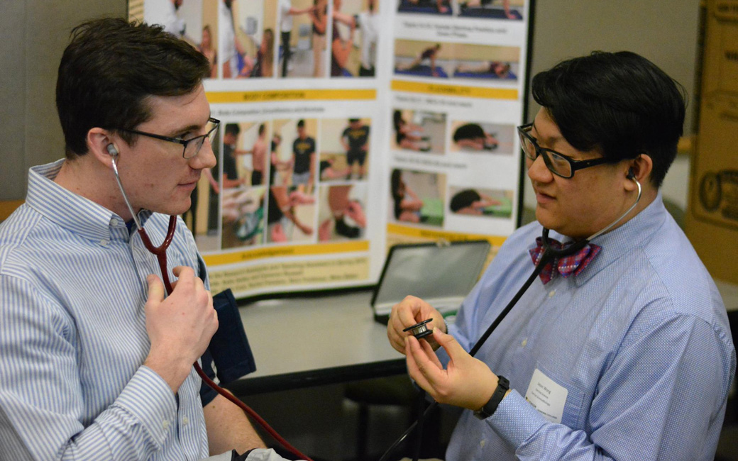 Student demonstrating research in front of poster