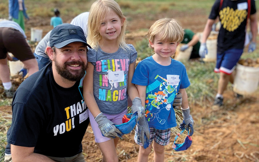 Justin Piche and his two children in a field smiling