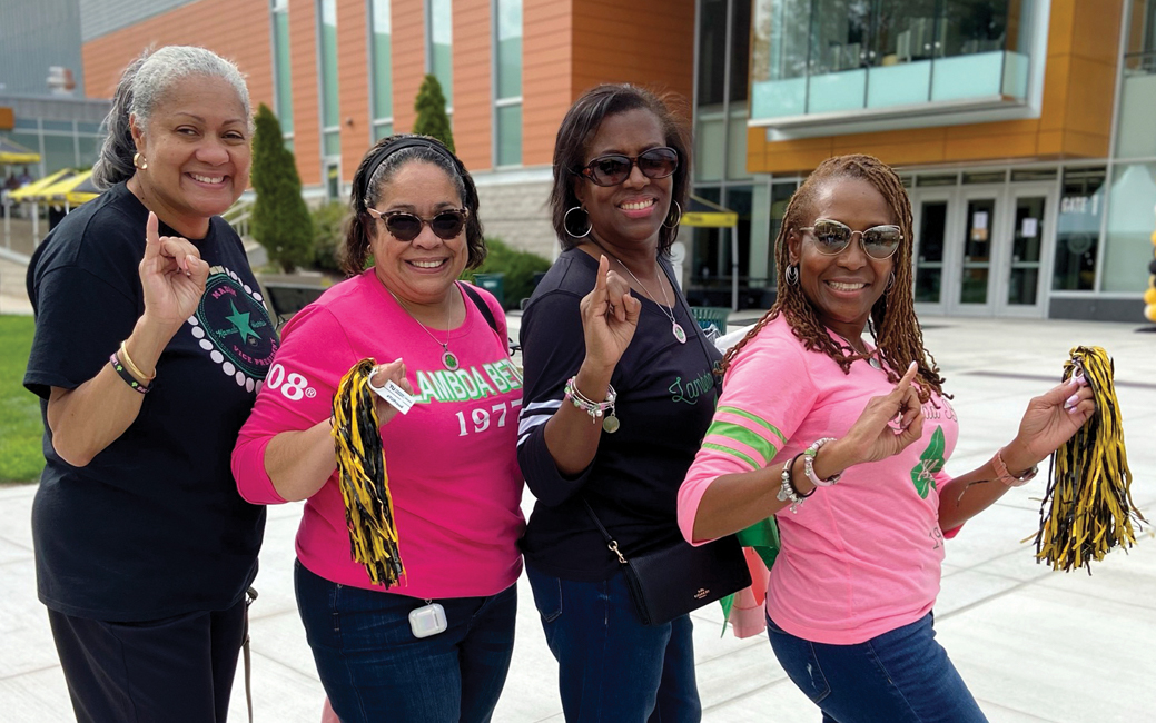 Four people outside SECU Arena holding up their pinkies and smiling