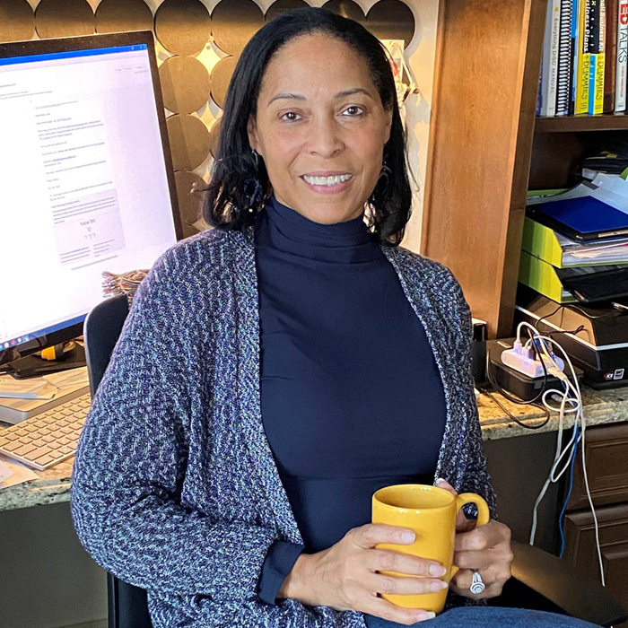 Linda Singh sitting with a cup of coffee