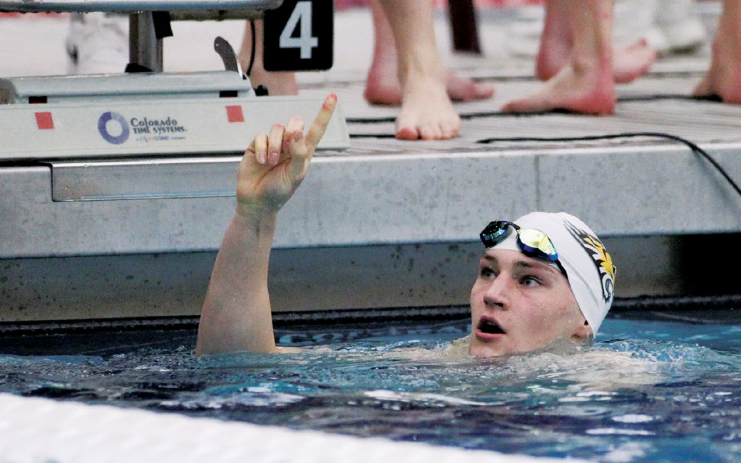 Male swimmer in water holding up his hand