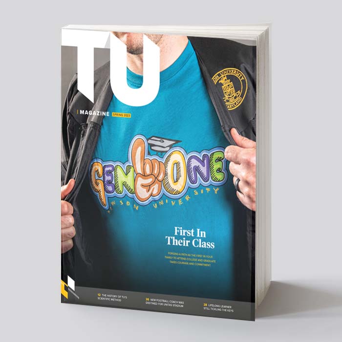 Magazine cover - a grad opening his shirt to reveal a Gen One T shirt