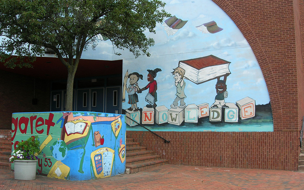 Mural of kids standing on top of letter blocks that spell out "knowledge" holding up a book