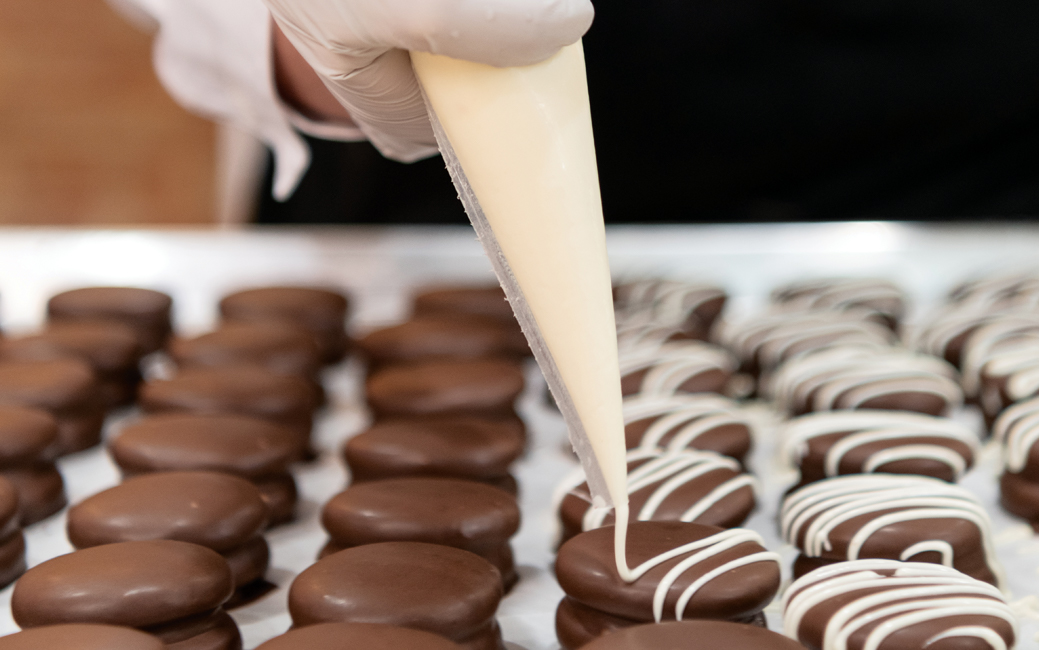 Woman's hand holding a pastry bag, icing cookies