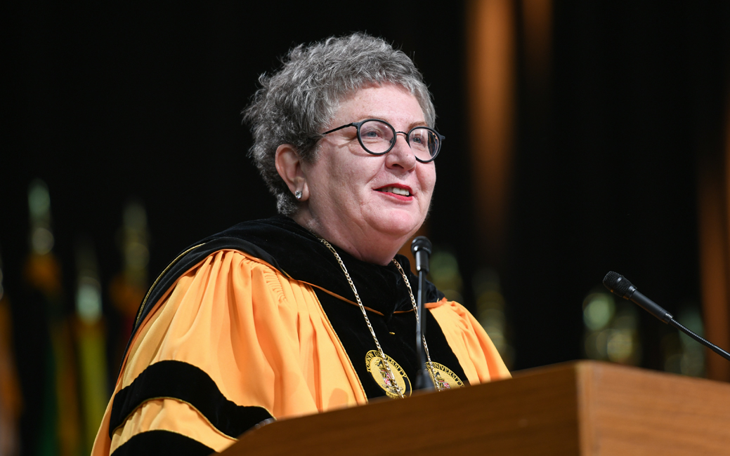 President Kim Schatzel at lecturn in regalia