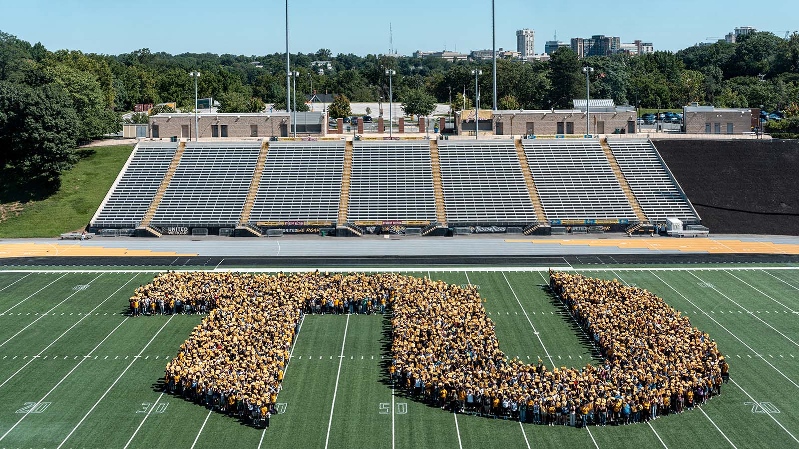students standing on a field in the shape of the letters TU