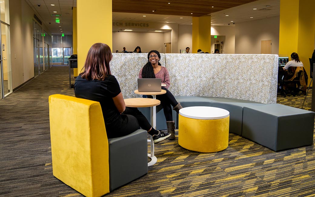 Student at laptop sits at couch study area