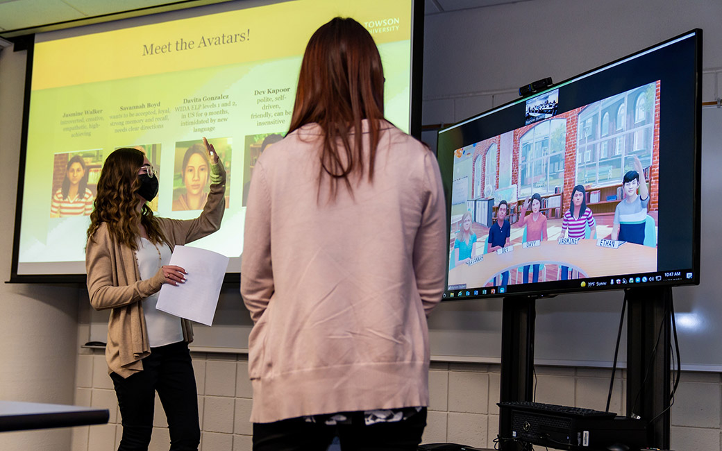 Stuents address a large screen with a virtual classroom of student avatars