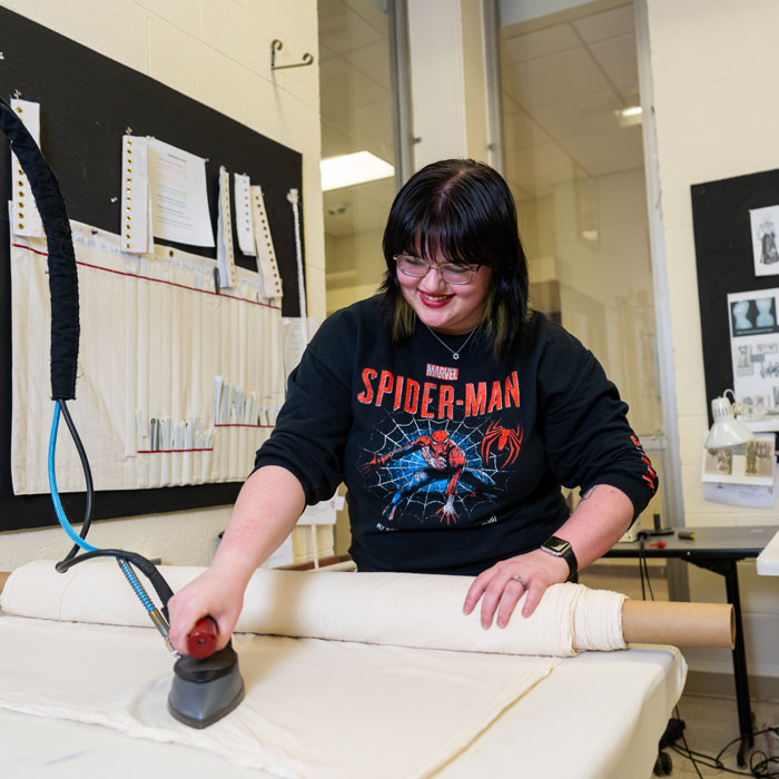 Student in the Costume Shop irons fabric