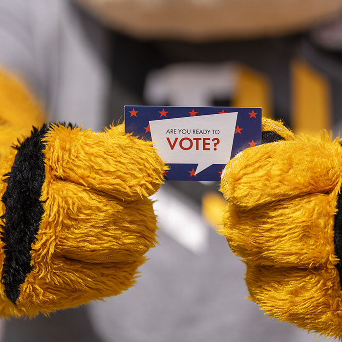 Doc hands holding a sticker that says "do you vote?"