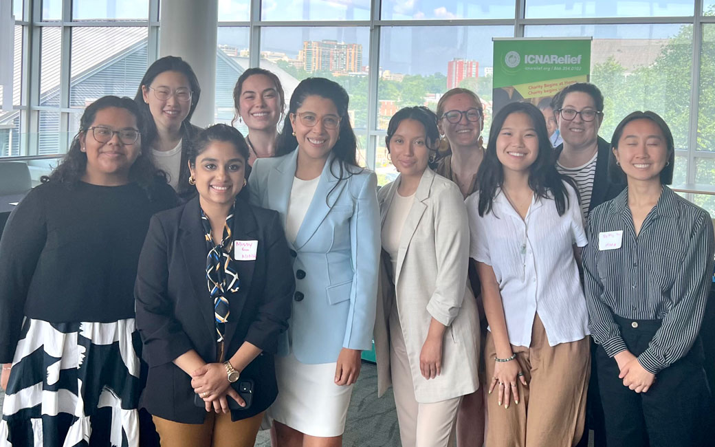 Ten women in business casual attire stand together