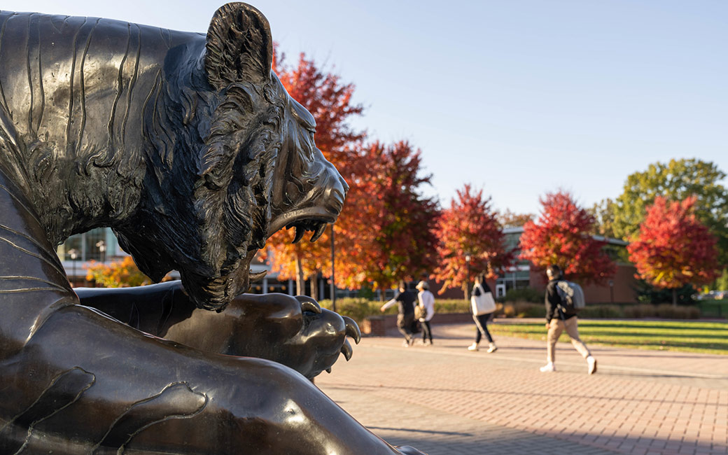 Tiger statue with students and fall trees