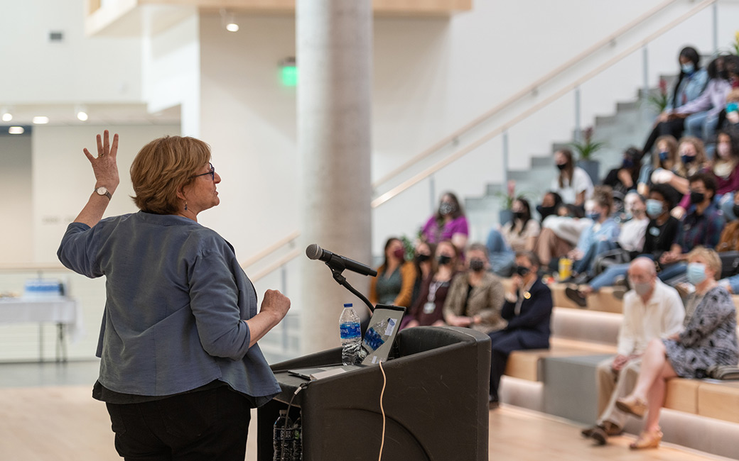 Woman at podium with crowd in background