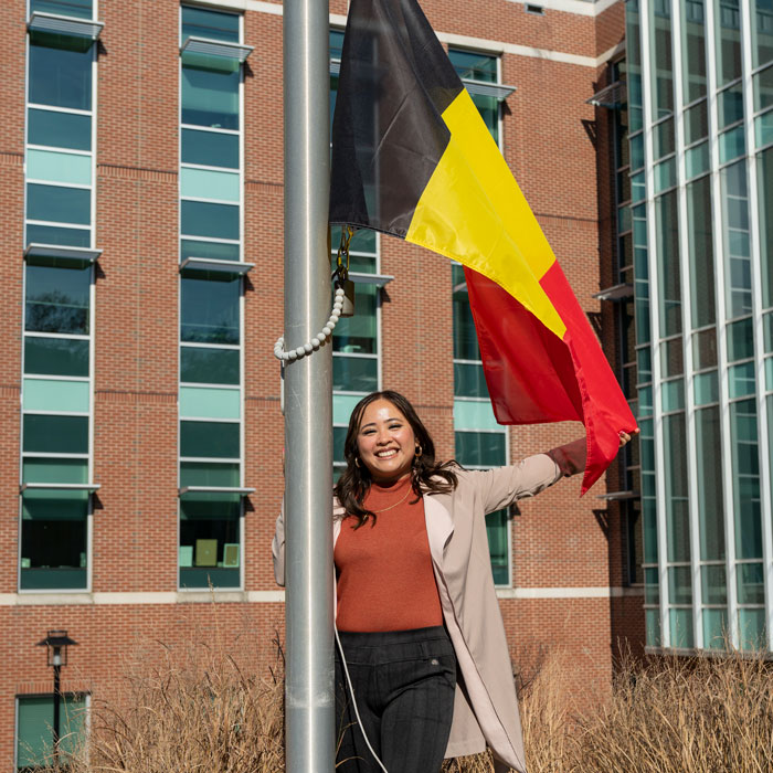 Alumna Sydney Avelino raises the Phillippines flag on International Walkway