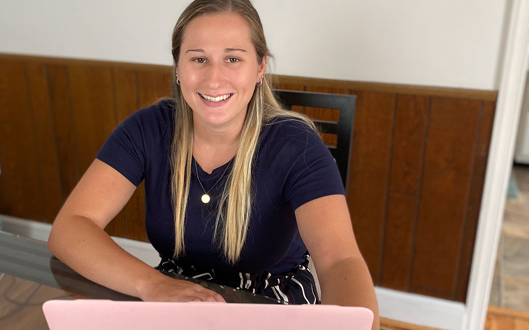 Laura Marsico sits at dining table in front of laptop