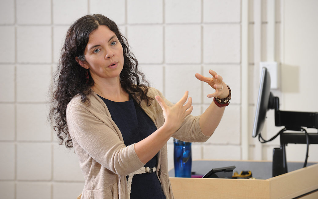 Woman teaching in front of podium with computer