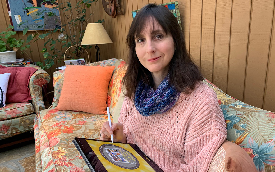 Professor Lynn Tomlinson sits on her couch with an iPad and stylus in her hand