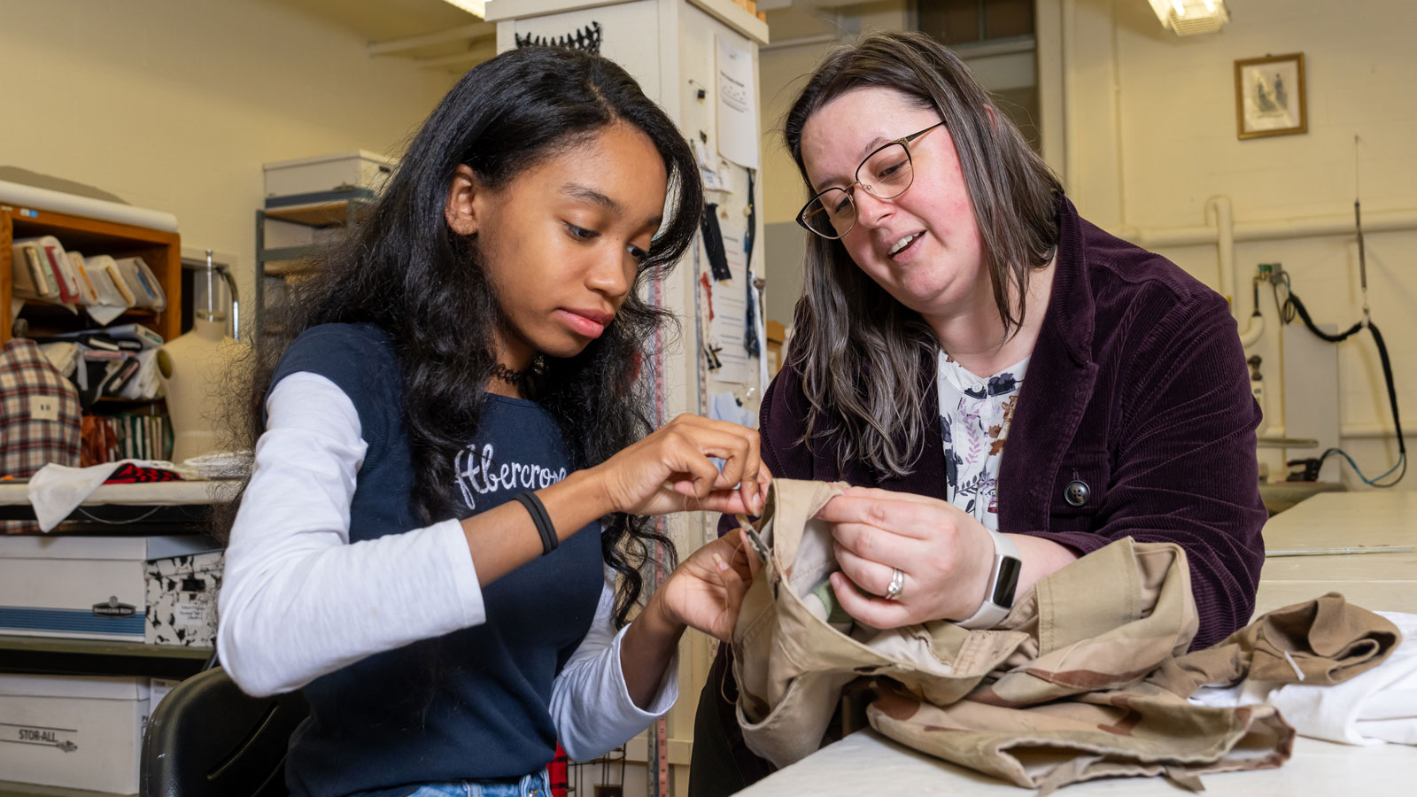 Costume shop manager Alizon Santamaria assists a student with hand sewing techniques