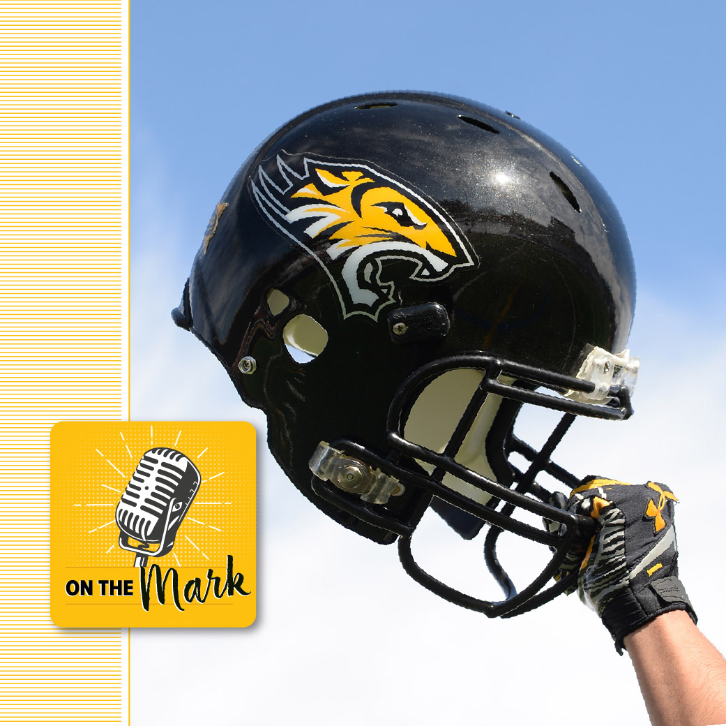 a hand holding a TU football helmet