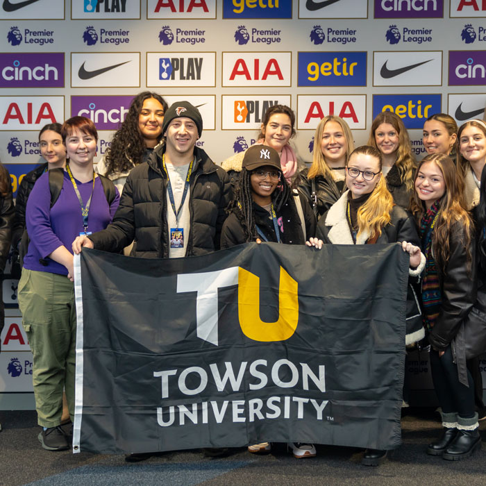 Students studying abroad hold Towson University flag