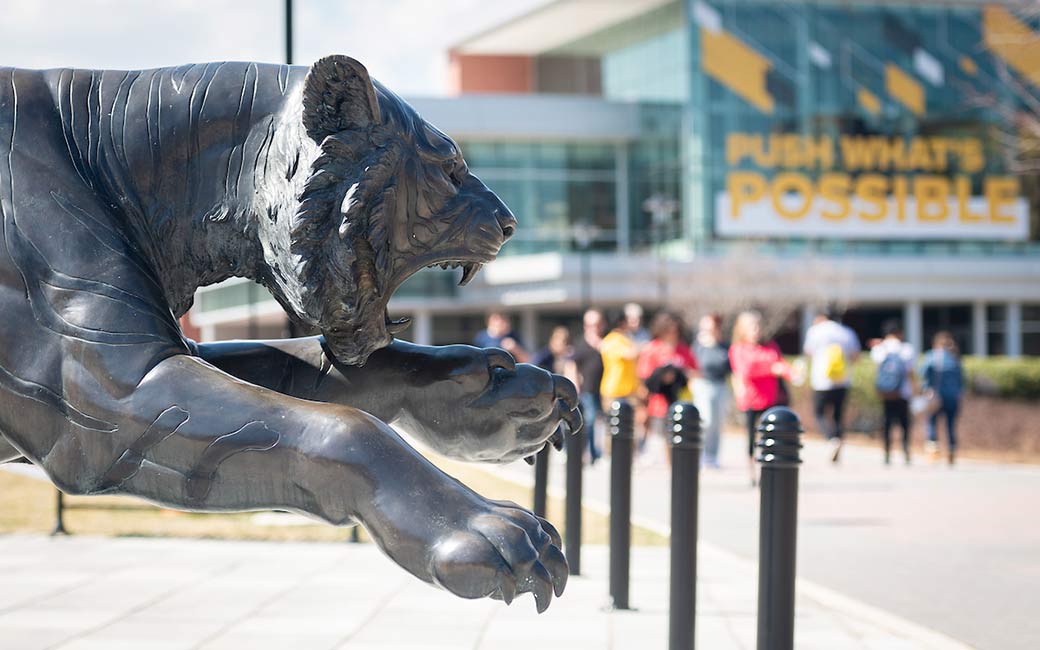 Tiger statue with people walking in background