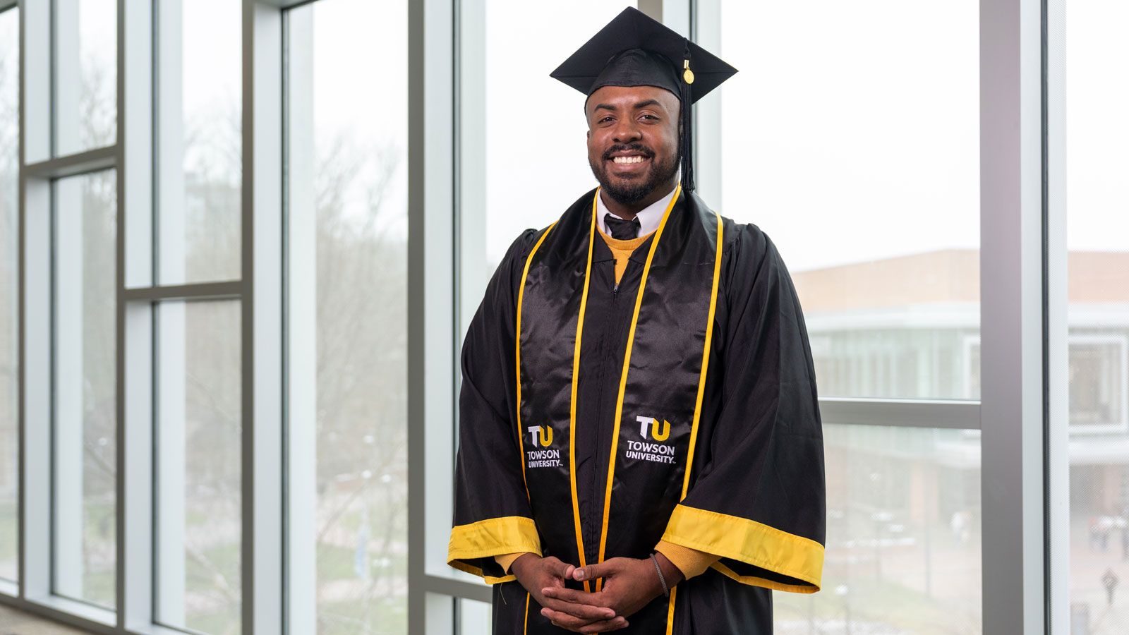 Commencement speaker Tyler Story stands in the union wearing his regalia