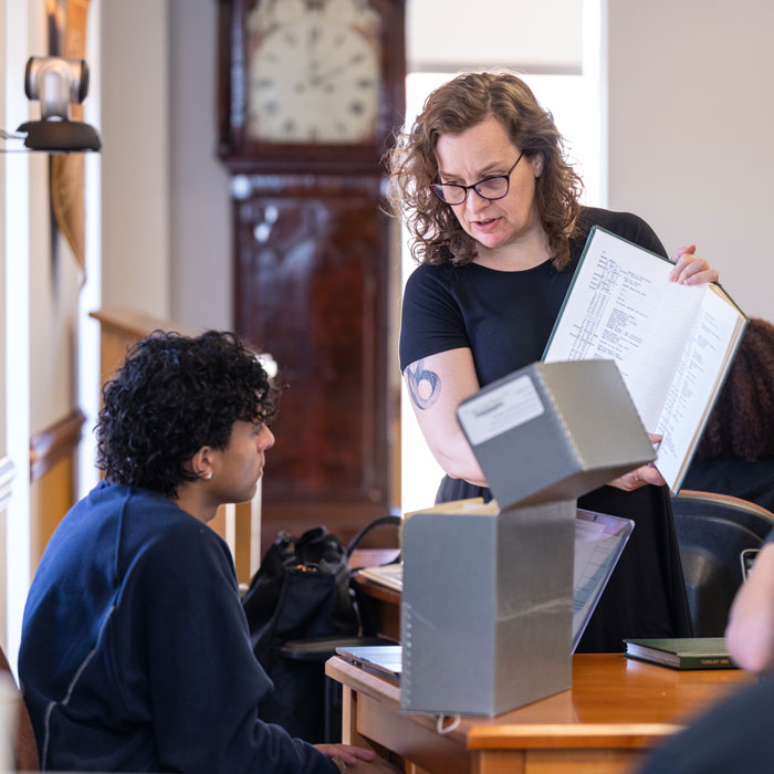 Student observes university archive texts with professor in the Towson Room