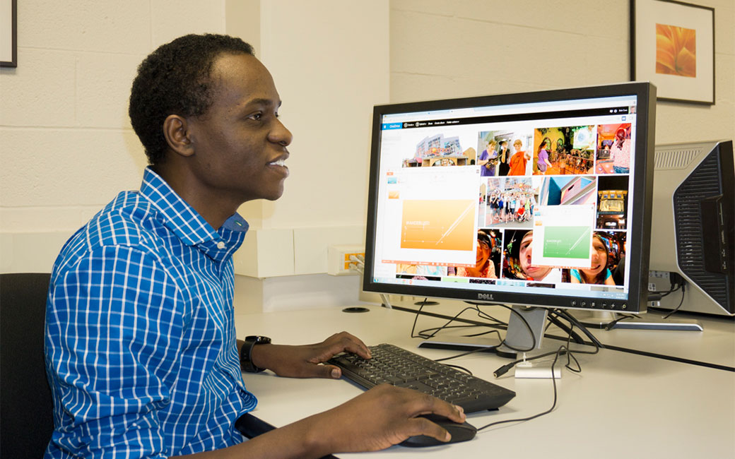 Student in blue shirt working at a Technology Support Desk lab computer