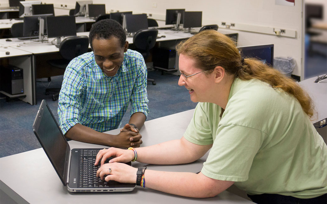 Staff person providing laptop assistance to a student at the Technology Support Desk Service Desk